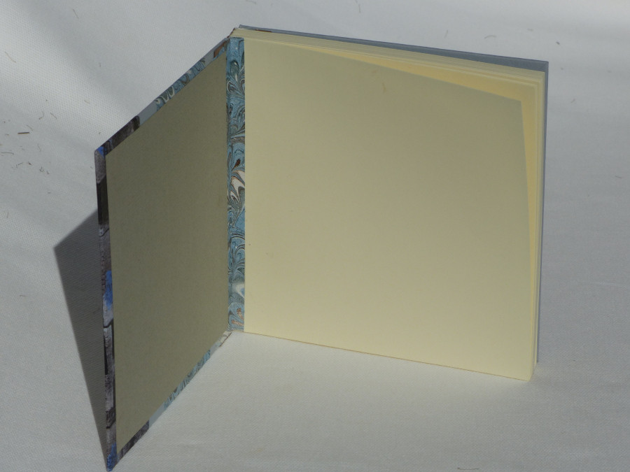 Carnet carré dos en cuir marron, papiers bleu et marron