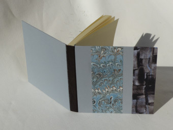 Carnet carré dos en cuir marron, papiers bleu et marron
