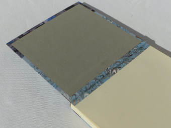 Carnet carré dos en cuir marron, papiers bleu et marron